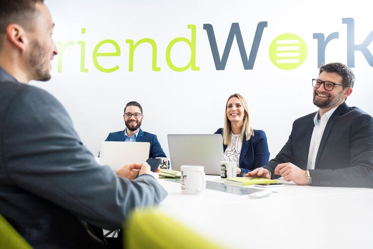 Vier Mitarbeitende der friendWorks GmbH lachend am Konferenztisch